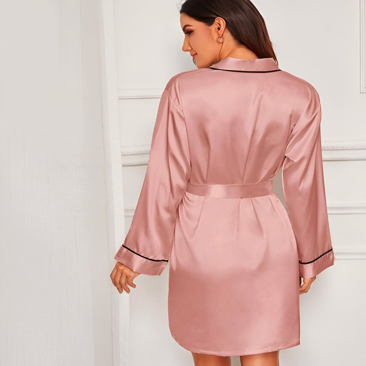 Femme portant un kimono rose en satin avec une ceinture, vêtement de détente élégant et confortable. Découvrez notre collection de kimonos uniques.