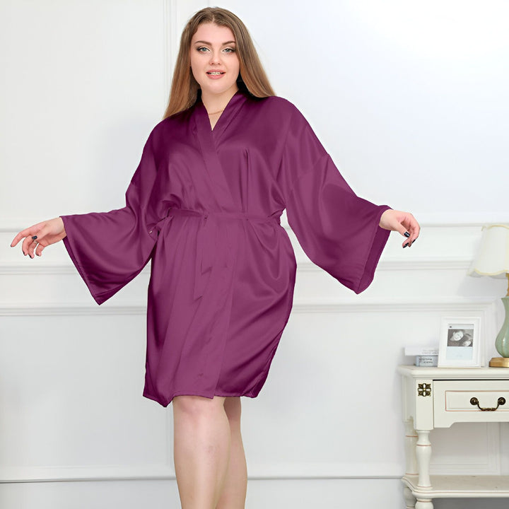 Femme portant un kimono violet en satin, manches larges et ceinture assortie. Kimono élégant et confortable, idéal pour se détendre à la maison. Découvrez notre collection de kimonos de qualité.