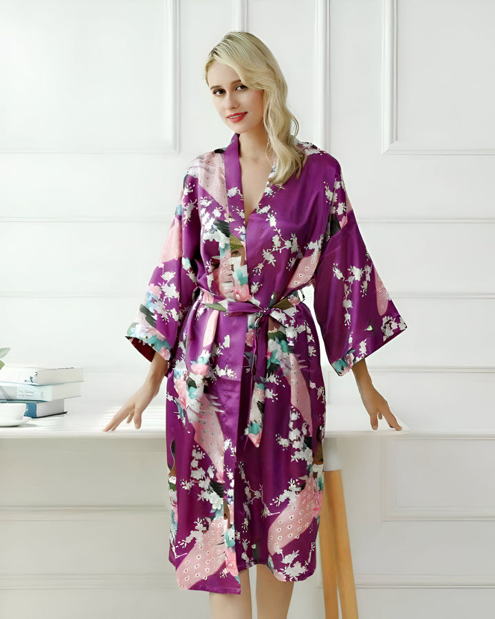 Femme portant un kimono violet à motifs floraux et de paons, ceinture assortie. Élégant peignoir pour se détendre avec style. Kimonos pour femmes, vêtements d'intérieur de luxe.