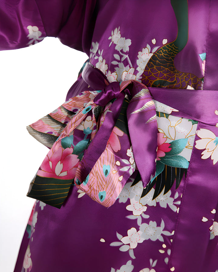 Gros plan d'un kimono violet avec motifs floraux et de paon, noué à la taille par une ceinture en tissu assorti. Vêtement traditionnel japonais, idéal pour se détendre avec style.