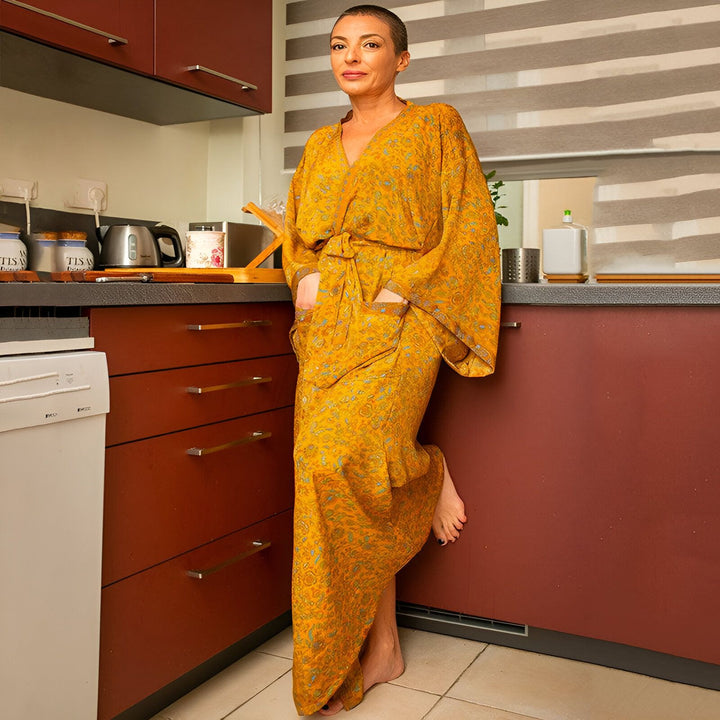 Femme portant un kimono jaune à motifs dans une cuisine. Vêtement d'intérieur élégant et confortable. Kimonos de qualité disponibles à l'achat.