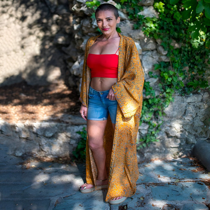 Femme portant un kimono jaune à motifs, crop top rouge et short en jean. Mode kimono, vente de kimonos en ligne. Style décontracté et élégant.