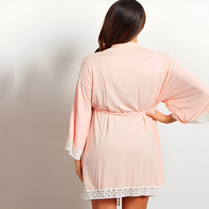 Femme vue de dos portant un kimono rose pâle avec bordure en dentelle. Kimono élégant et confortable disponible à l'achat.