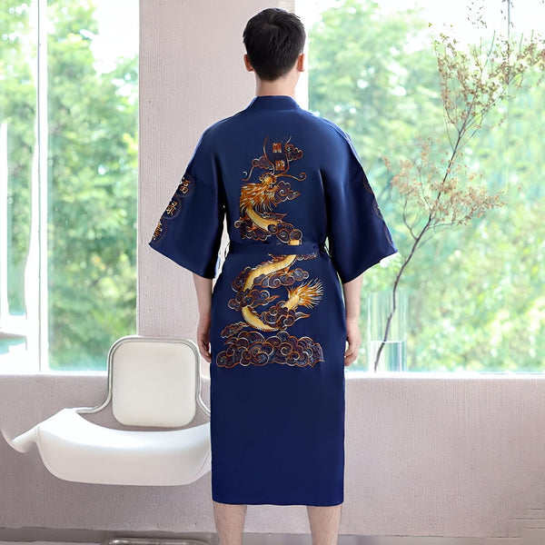 Homme portant un kimono bleu marine avec broderie de dragon doré dans un intérieur lumineux. Vêtement traditionnel japonais disponible à l'achat.