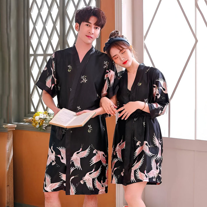Couple portant des kimonos assortis noirs avec motif de grues roses et blanches. Robes de chambre japonaises élégantes, vente de kimonos en ligne.