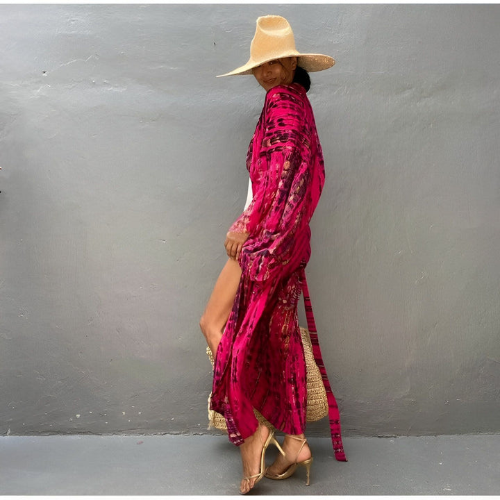 Femme portant un kimono rose vif à motifs, chapeau de paille et talons dorés. Parfait pour une journée ensoleillée. Découvrez notre collection de kimonos uniques et élégants.