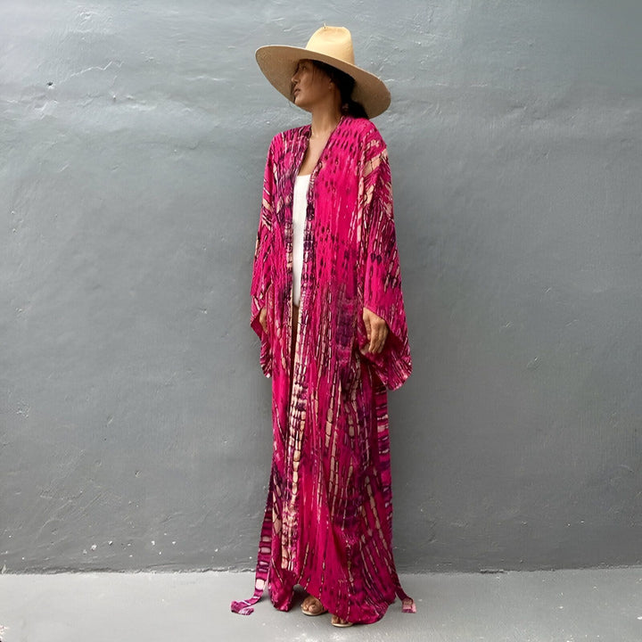 Femme portant un kimono long rose vif à motifs, et un chapeau de paille. Collection de kimonos tendance pour femme.