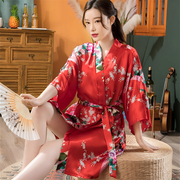 Femme portant un kimono rouge à motifs floraux, tenant un éventail. Vente de kimonos en ligne.