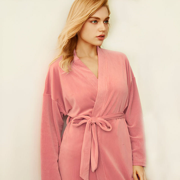 Femme blonde portant un kimono rose en velours avec une ceinture. Vente de kimonos confortables et élégants.