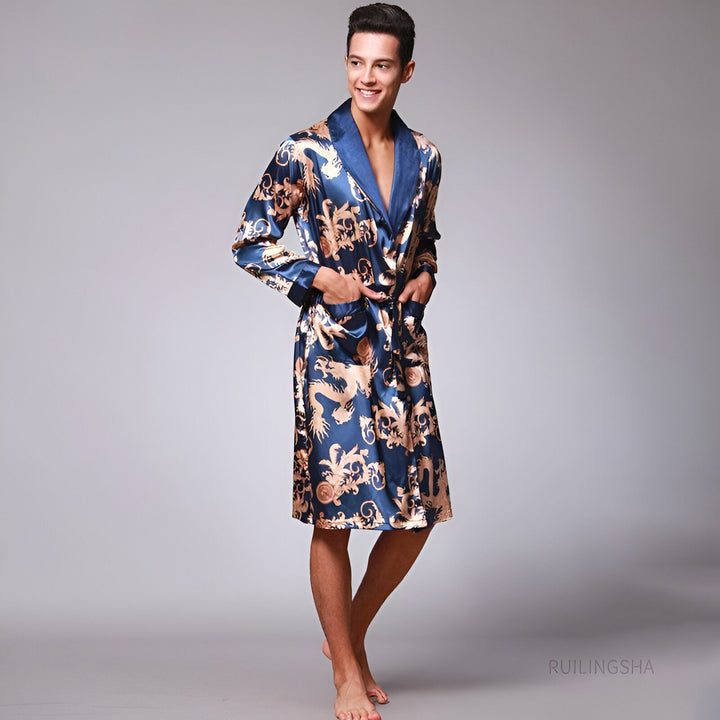 Homme souriant portant un kimono bleu en soie avec motifs dorés. Peignoir luxueux de notre collection.