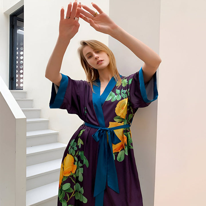 Femme portant un kimono violet à motifs floraux jaunes. Vêtement de style japonais, idéal pour la maison ou les occasions spéciales. Découvrez notre collection de kimonos uniques.