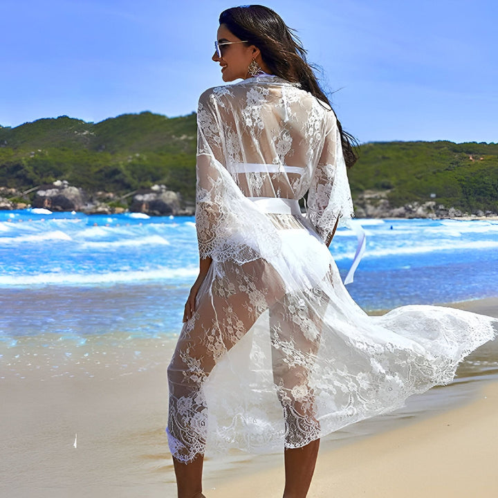 Femme portant un kimono de plage en dentelle blanche. Vêtement de plage transparent et élégant, idéal pour les vacances. Découvrez notre collection de kimonos pour l'été.