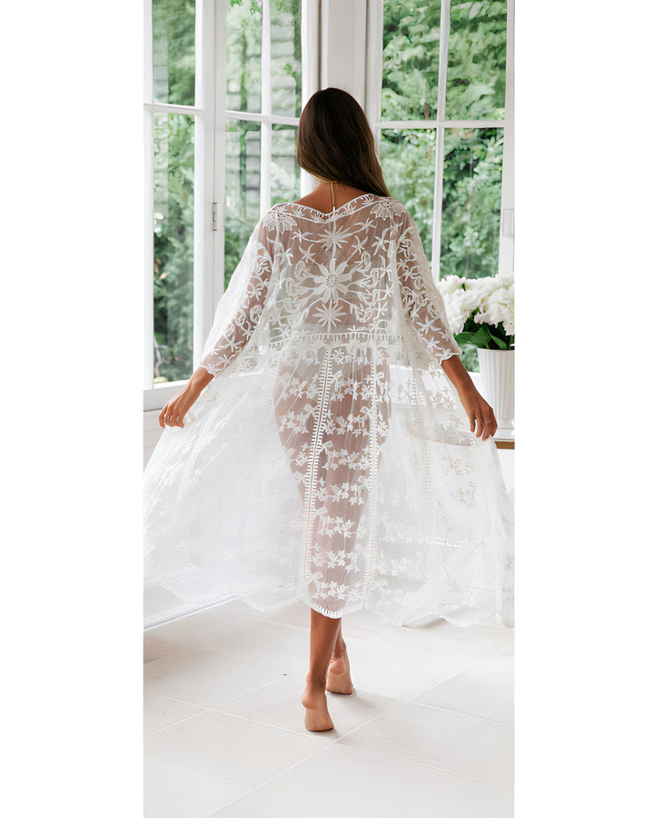 Femme portant un kimono blanc en dentelle devant une fenêtre. Vêtements de détente élégants. Achetez notre collection de kimonos.