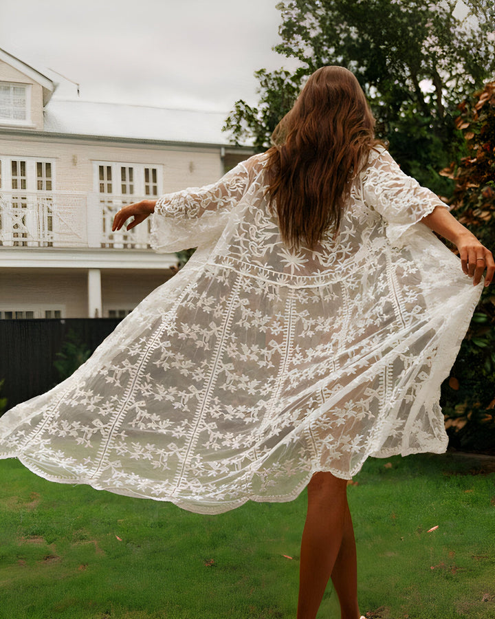 Femme portant un kimono blanc en dentelle avec des motifs floraux. Vue arrière, kimono flottant au vent dans un jardin. Vêtements de détente et de style bohème. Kimonos à motifs floraux.