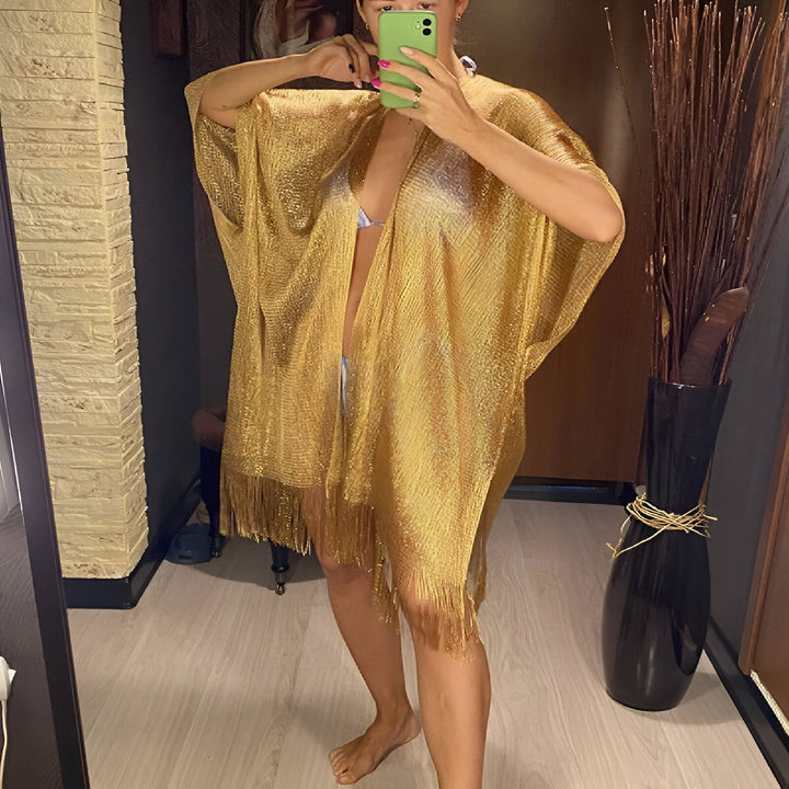 Femme portant un kimono doré à franges. Vêtements de plage élégants, parfait comme pardessus léger. Découvrez notre collection de kimonos uniques.