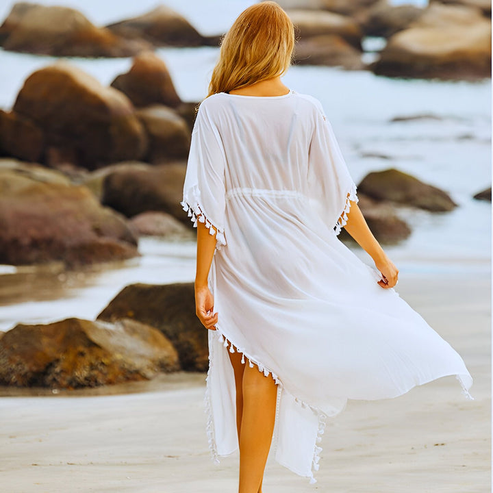 Femme portant un kimono blanc sur la plage. Kimono de plage avec pompons, vêtement d'été léger et élégant.