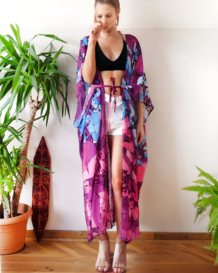 Femme portant un kimono long violet et bleu avec un short blanc et un haut noir. Kimono tendance pour femme, idéal pour l'été. Découvrez notre collection de kimonos élégants.