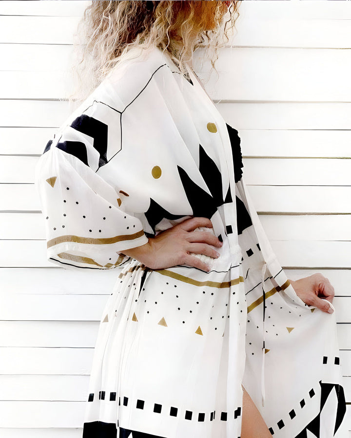 Kimono pour femme avec motifs géométriques noirs, blancs et or. Vêtement ample et confortable. Idéal pour un look bohème chic. Notre collection de kimonos uniques est disponible en ligne.