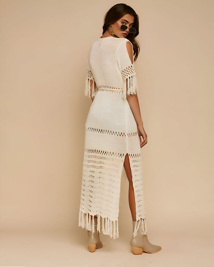 Femme portant une longue robe kimono blanche en crochet avec des franges. Kimono d'été ajouré avec des manches courtes et des découpes aux épaules. Robe kimono fendue.
