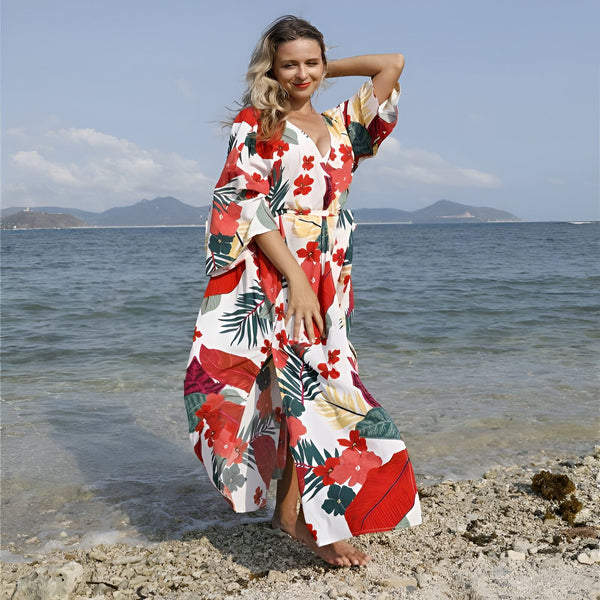 Femme souriante portant un kimono fleuri sur une plage ensoleillée. Kimonos de plage élégants et colorés en vente.