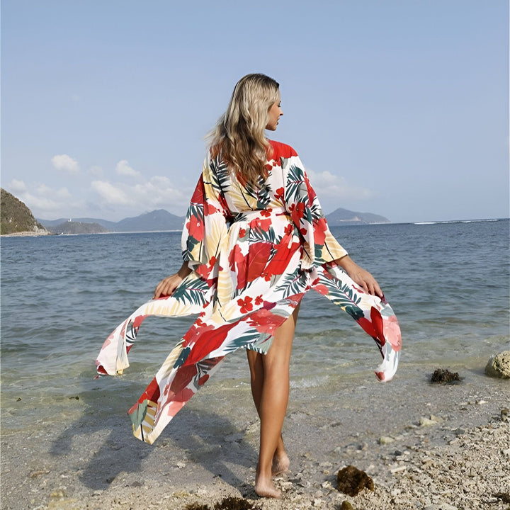 Femme blonde portant un kimono à motifs floraux sur une plage ensoleillée. Kimonos pour femmes disponibles à l'achat. Mode plage et vêtements d'été.