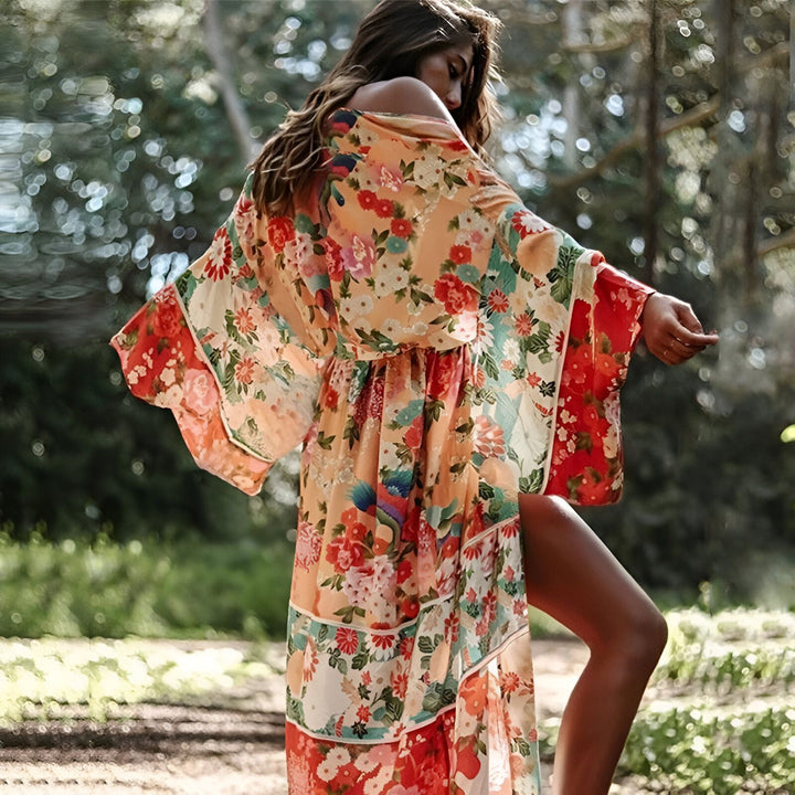 Femme portant un kimono long à motifs floraux orange et rouge. Vêtements de plage et d'été bohèmes. Collection de kimonos floraux pour femmes.