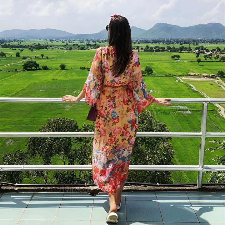 Femme portant un kimono fleuri, admirant le paysage verdoyant. Vente de kimonos en ligne. Découvrez notre collection de kimonos uniques et colorés.