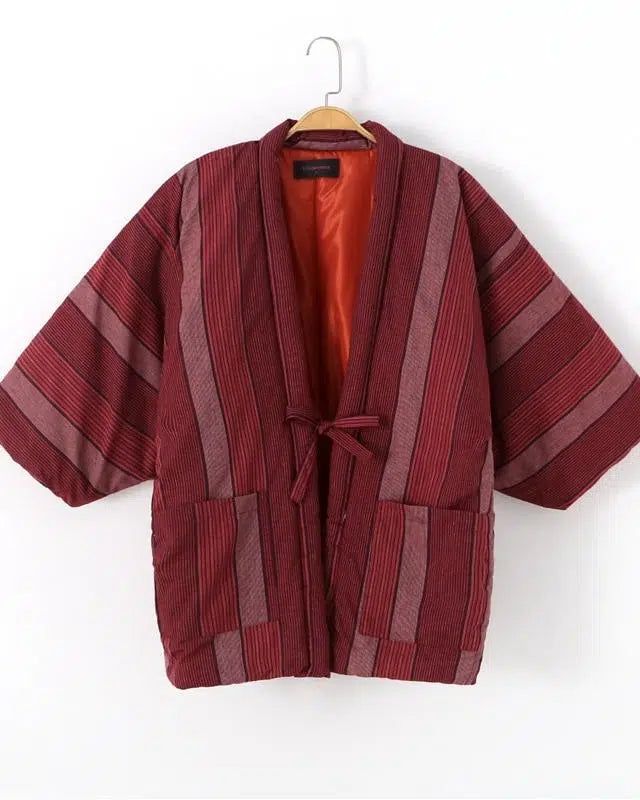 Kimono japonais rayé rouge et bordeaux suspendu. Vêtement traditionnel avec poches et ceinture à nouer. Doublure orange. Boutique de kimonos authentiques.