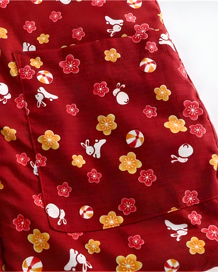 Détail d'un kimono rouge avec un motif floral, des lapins et des bonbons japonais traditionnels. Vêtement japonais parfait pour une allure unique. Explorez notre collection de kimonos.
