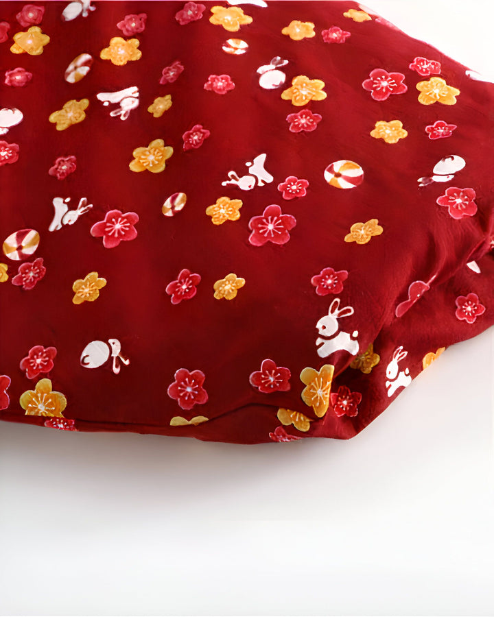 Motif de fleurs, lapins et bonbons sur tissu rouge bordeaux. Détail d'un kimono japonais. Vêtements traditionnels.