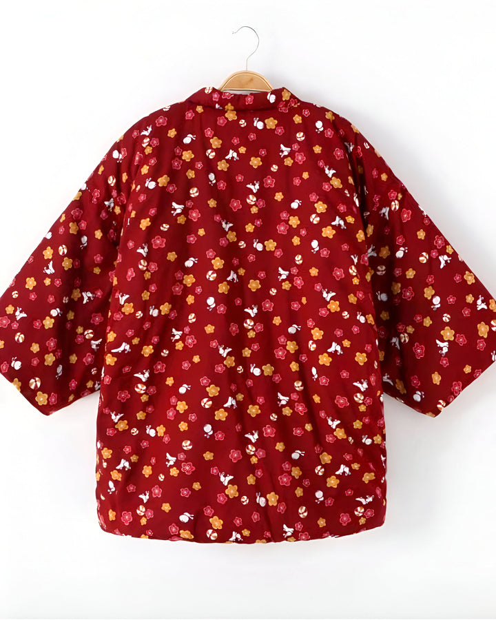 Kimono rouge à motifs floraux et oiseaux, suspendu sur un cintre. Vêtement traditionnel japonais, idéal pour un look tendance et original. Découvrez notre collection de kimonos uniques !