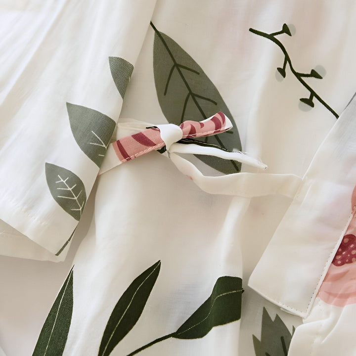 Détail d'un kimono blanc à motifs floraux et nœud décoratif rose. Gros plan sur le tissu léger et les motifs délicats, idéal pour un style japonais authentique. Découvrez notre collection de kimonos.