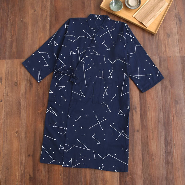Kimono bleu marine à motifs constellations blanches, présenté à plat sur fond bois. Vêtement japonais confortable et élégant.