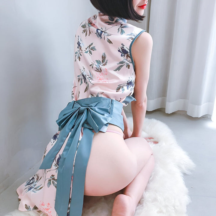 Femme portant un kimono rose à motifs floraux, noué avec une ceinture bleue à gros nœud. Vue arrière, mise en valeur du vêtement. Vêtements traditionnels japonais revisités, disponibles à l'achat.
