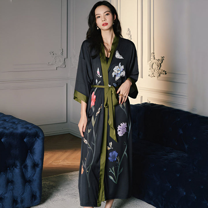 Femme portant un kimono long noir avec des motifs floraux et une ceinture verte. Kimono élégant et confortable à vendre.