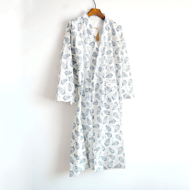 Kimono blanc à motifs de plumes bleues suspendu à un cintre. Vêtement confortable et élégant, idéal pour se détendre à la maison. Découvrez notre collection de kimonos uniques.