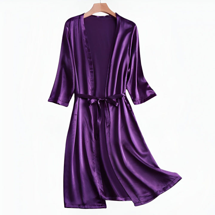 Kimono violet en satin, avec ceinture, suspendu sur un cintre. Vêtement d'intérieur élégant et confortable, idéal pour se détendre avec style. Découvrez notre collection de kimonos.