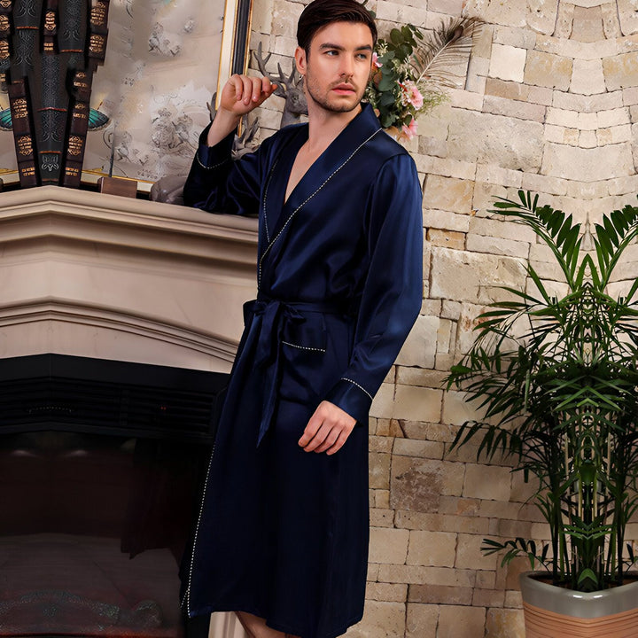 Homme élégant en kimono bleu marine, adossé à une cheminée. Vêtements de détente de luxe, peignoir en soie, collection kimono pour hommes. Achetez votre kimono idéal.