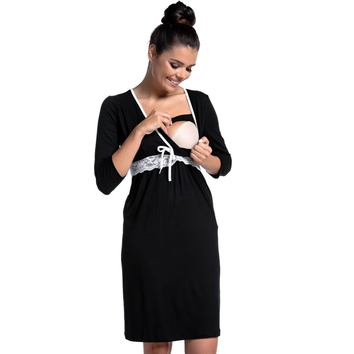 Femme portant une robe de maternité noire avec détails en dentelle blanche. Design pratique pour l'allaitement. Kimono confortable et élégant pour la maternité.