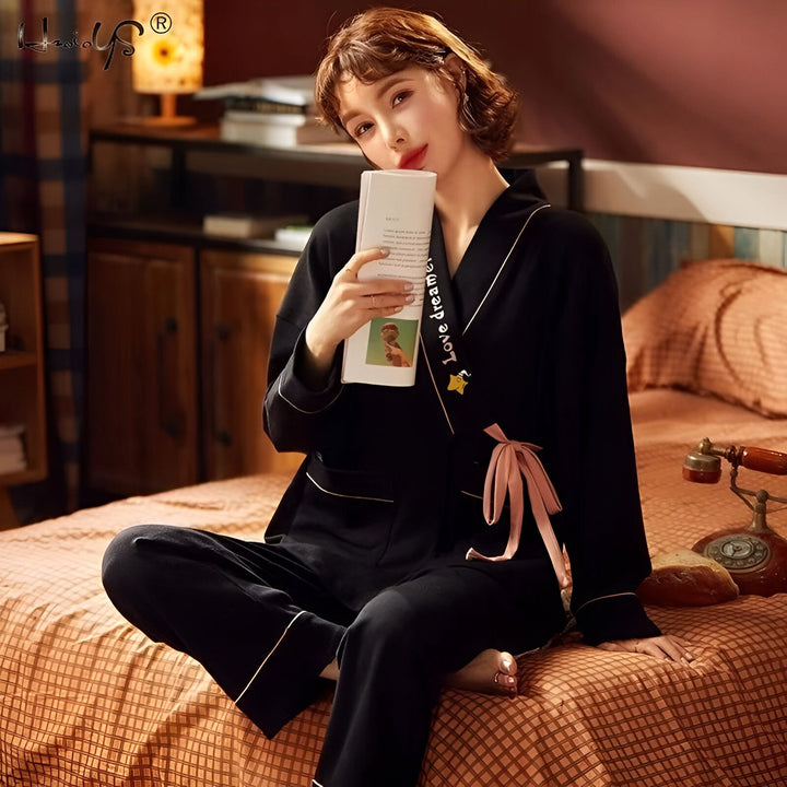 Femme en kimono noir avec bordure rose lisant. Kimono élégant pour la maison ou la détente. Découvrez notre collection de kimonos confortables et chics.