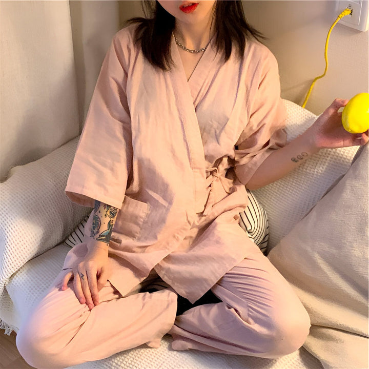 Femme assise en tailleur portant un kimono rose clair. Vente de kimonos pour femmes, style japonais. Détente à la maison.