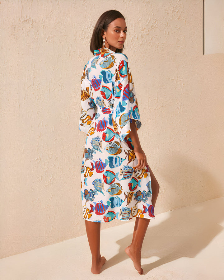 Femme portant un kimono blanc à motifs de poissons colorés. Vêtement d'intérieur ou de plage élégant. Kimonos disponibles à l'achat en ligne.