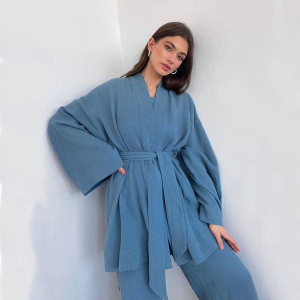 Femme portant un kimono bleu clair avec ceinture assortie. Vêtements kimono confortables et élégants. Découvrez notre collection de kimonos.