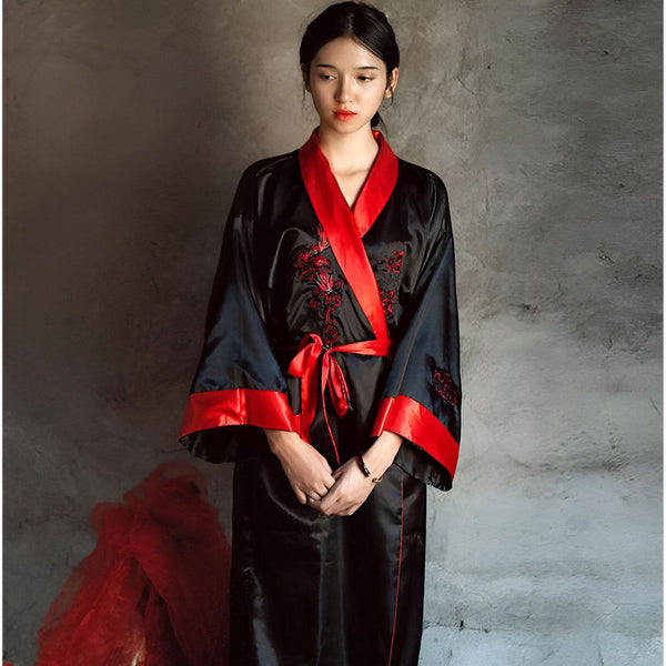 Jeune femme portant un kimono noir et rouge avec des broderies florales. Kimono traditionnel, vêtement japonais, mode asiatique. Boutique de kimonos en ligne.