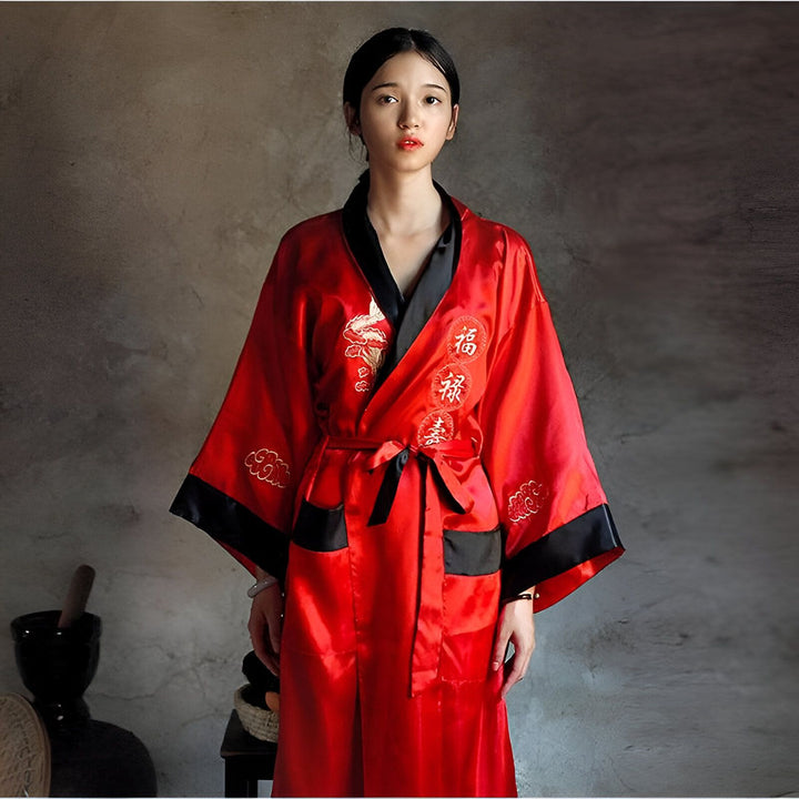 Femme portant un kimono rouge en satin avec broderies dorées et ceinture noire. Vêtement traditionnel japonais. Kimonos à vendre.