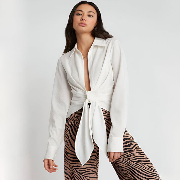 Femme portant une chemise blanche nouée et un pantalon zébré. Collection de kimonos modernes et élégants.