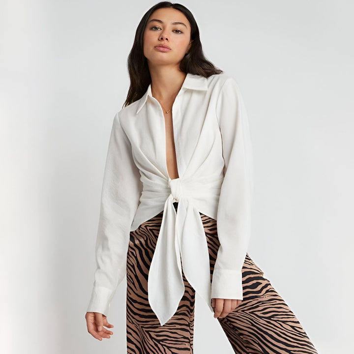 Femme portant une chemise blanche nouée et un pantalon zébré. Collection de kimonos modernes et élégants.