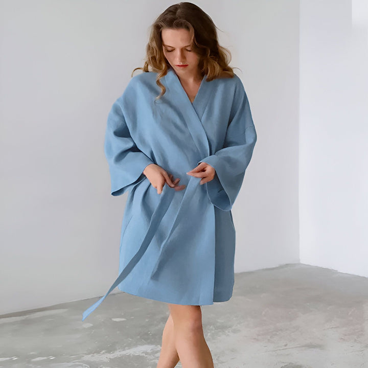 Femme portant un kimono bleu clair. Peignoir de style japonais, vêtement confortable et élégant. Idéal pour se détendre à la maison. Découvrez notre collection de kimonos.