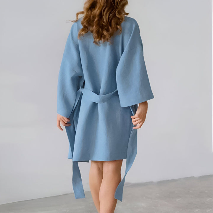 Dos d'une femme portant un kimono bleu clair en lin, avec une ceinture. Vêtements de détente confortables et élégants. Découvrez notre collection de kimonos uniques !
