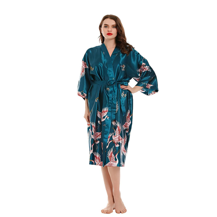 Femme portant un kimono bleu sarcelle avec des motifs de grues. Élégant vêtement d'intérieur, parfait comme robe de chambre ou peignoir. Nos kimonos sont disponibles dans différents styles et couleurs. Découvrez notre collection!